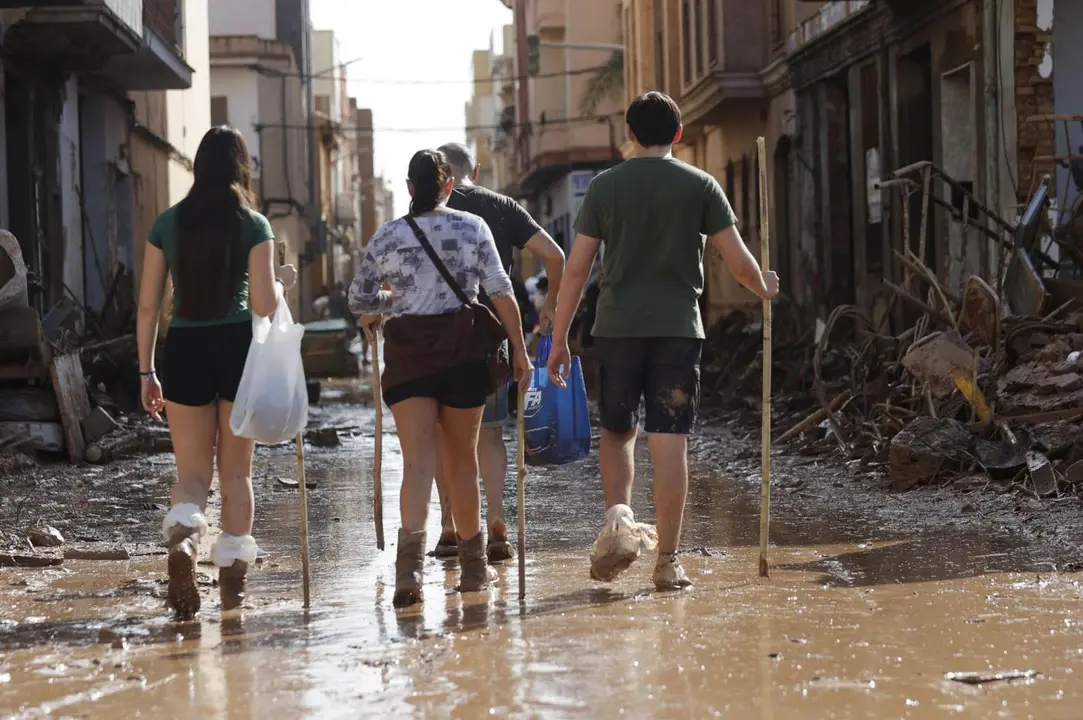 Varias personas caminan entre el lodo acumulado. - EFE/Manuel Bruque