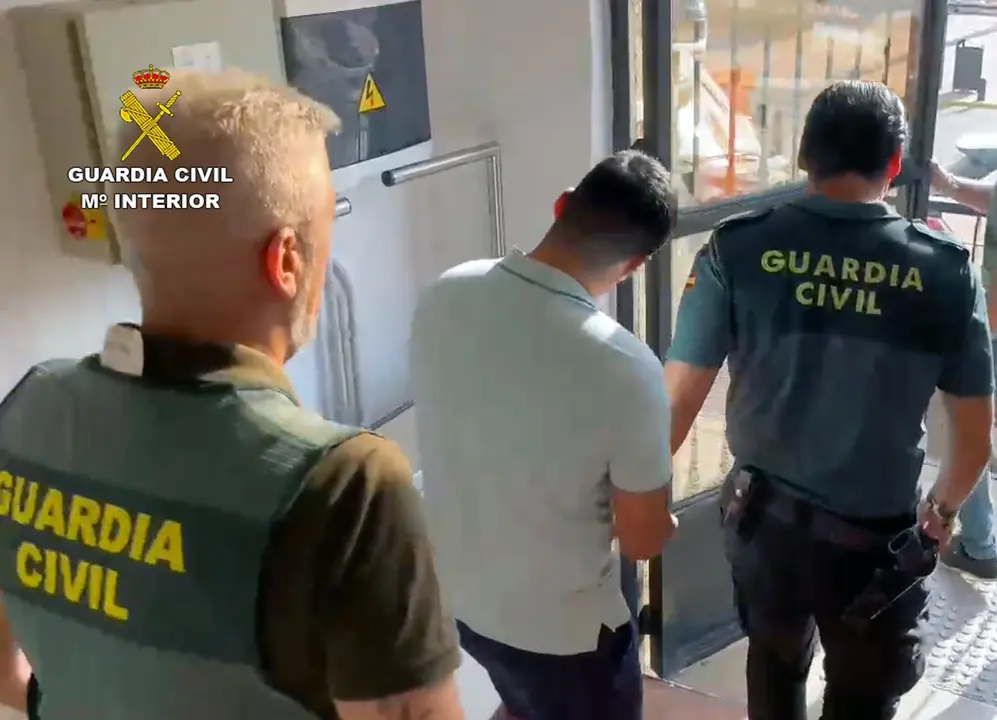 Uno de los detenidos es custodiado por dos agentes. | Europa Press.