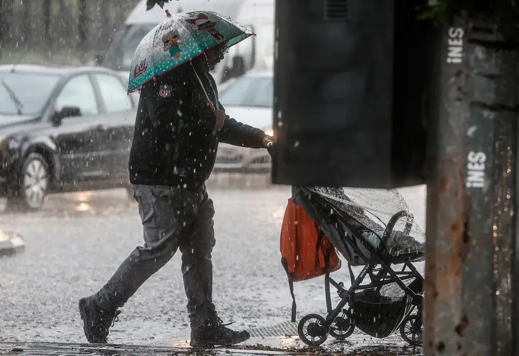 Un hombre lleva un carrito de beb&eacute; mientras se protege de la lluvia con un paraguas | Rober Solsona / Europa Press