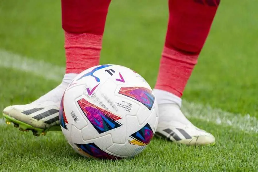 Los pies de un futbolista tocan el bal&oacute;n sobre el c&eacute;sped de un estadio de f&uacute;tbol. | LALIGA