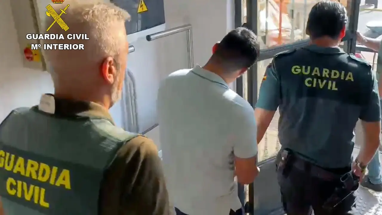 Uno de los detenidos es custodiado por dos agentes. | Europa Press.